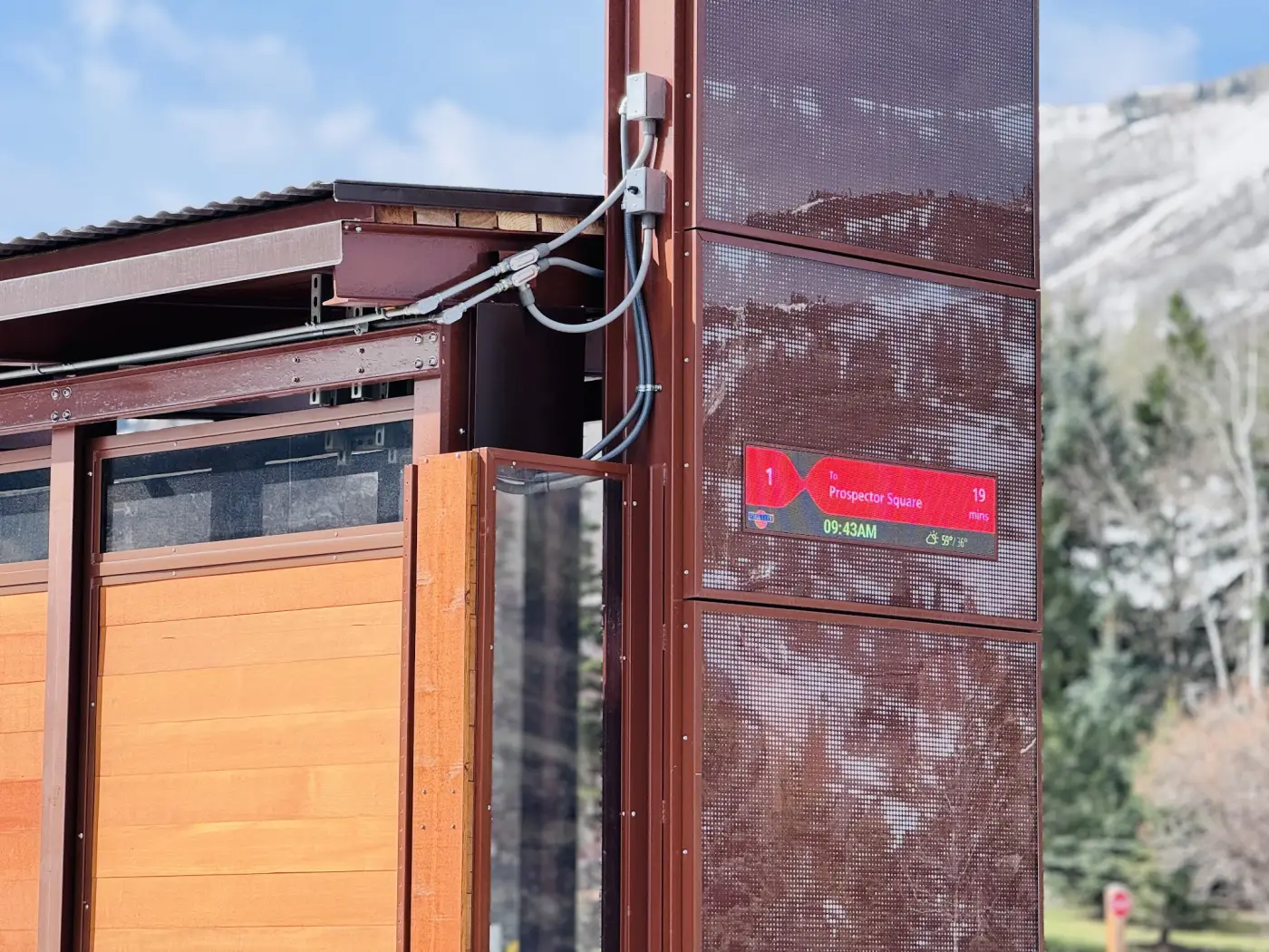 A full-matrix LED display integrated into a custom timber totem at a mountain stop.