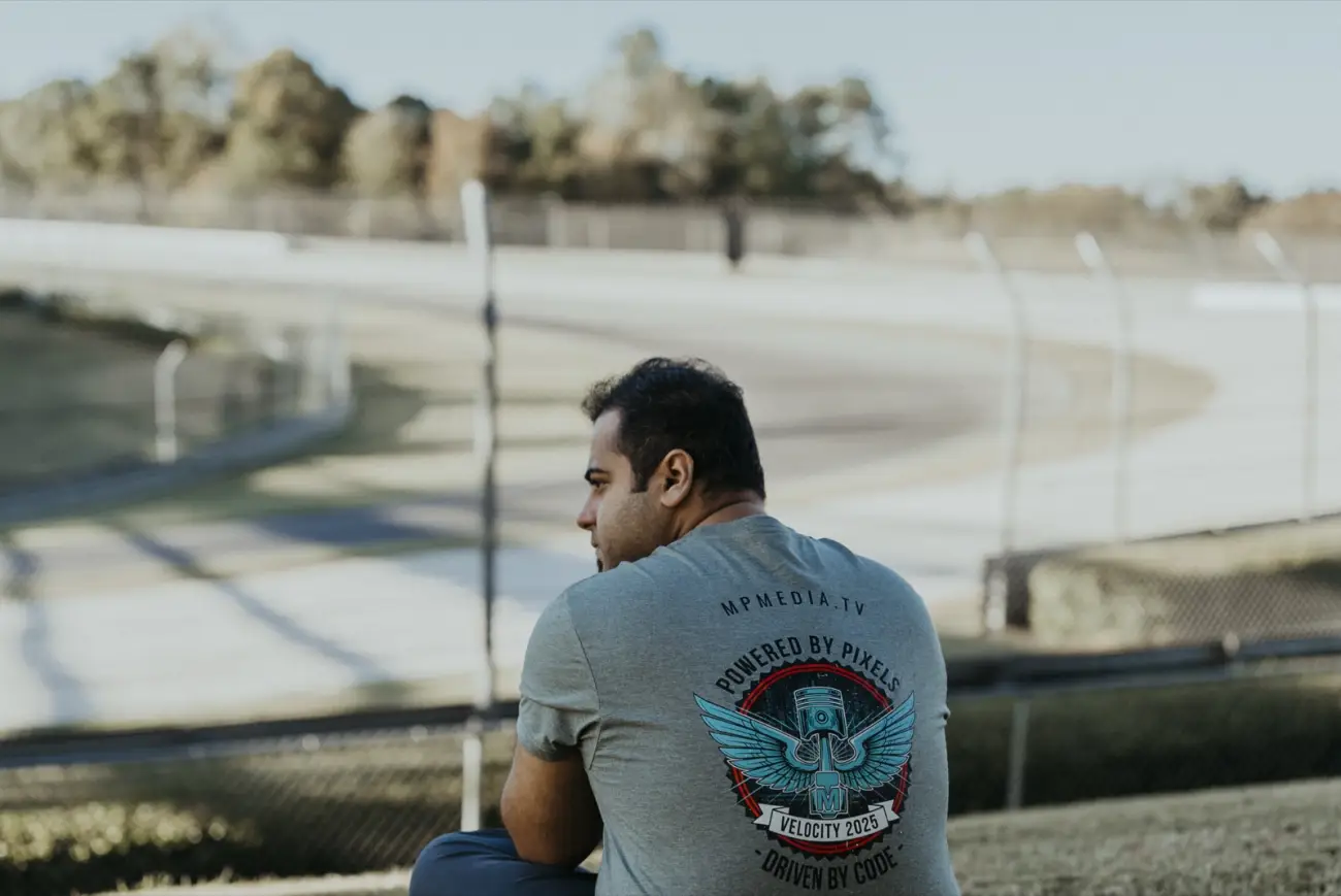 A crew member in a Powered by Pixels tee overlooking the Barber race track